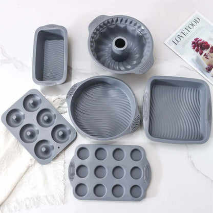 A versatile silicone baking pan set featuring six pieces, including a bundt pan, loaf pan, round pan, square pan, six-cavity donut pan, and twelve-cavity muffin pan. Crafted from durable, non-stick silicone, these pans ensure effortless release and even baking. The sleek gray design and ergonomic handles make them both functional and stylish, perfect for all your baking needs.