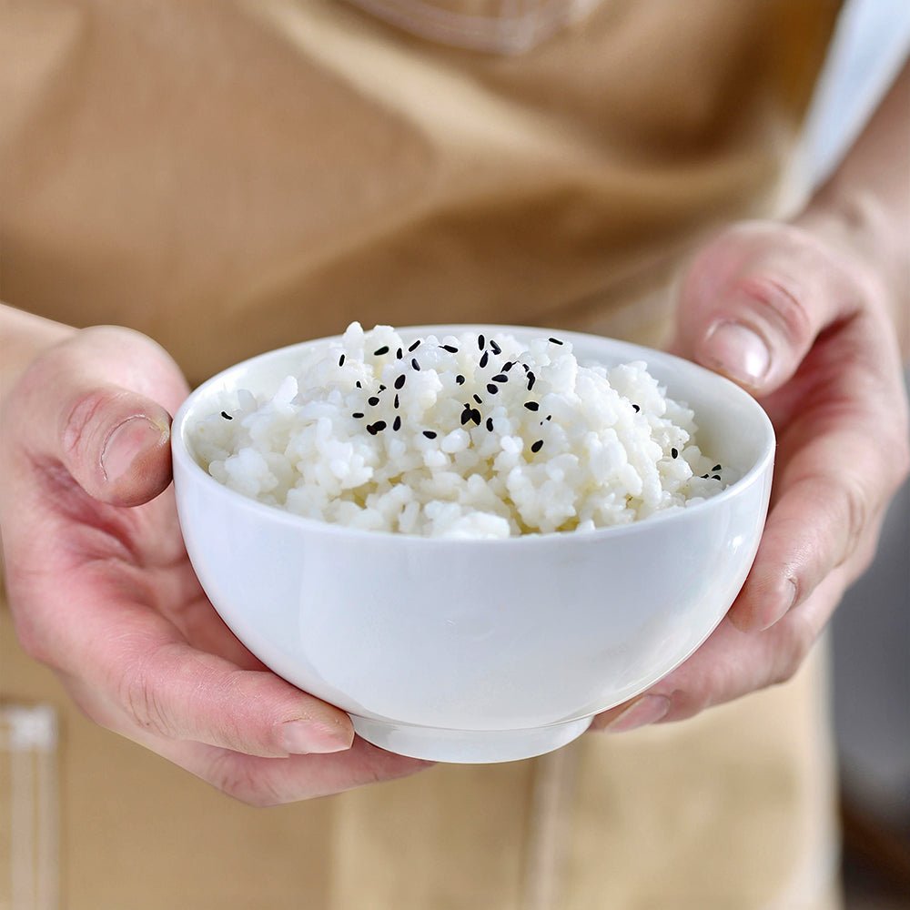 A woman holding a porcelain snack bowl full of rice.