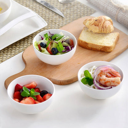 Three snacking bowls: one with fresh strawberries, another with noodles, and the third with salad and olives.