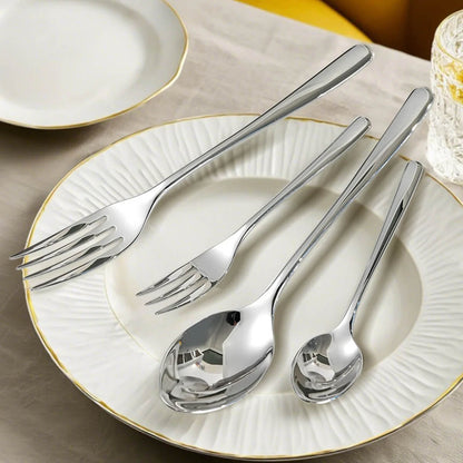 Stainless silverware sets with polished forks and spoons arranged neatly on a white plate with gold trim on a linen tablecloth.