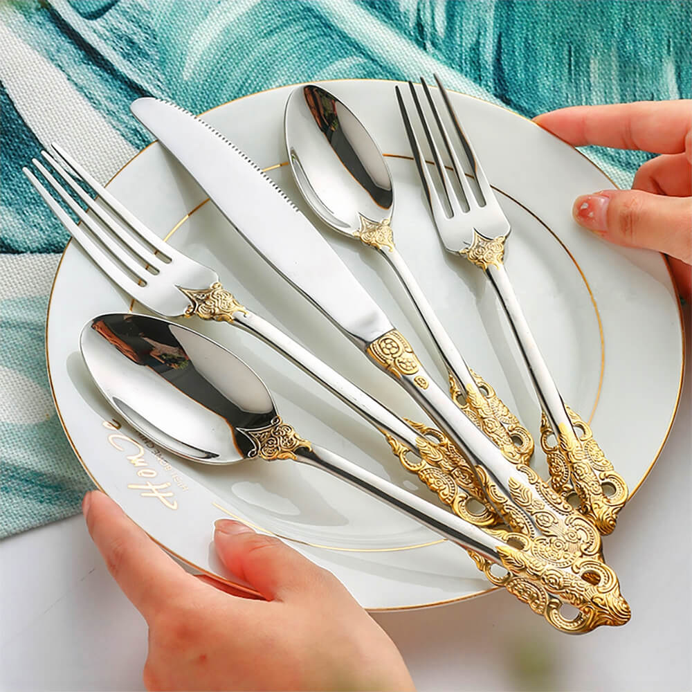 A woman holding a tainless steel flatware cutlery set, elegantly displayed on a plate.