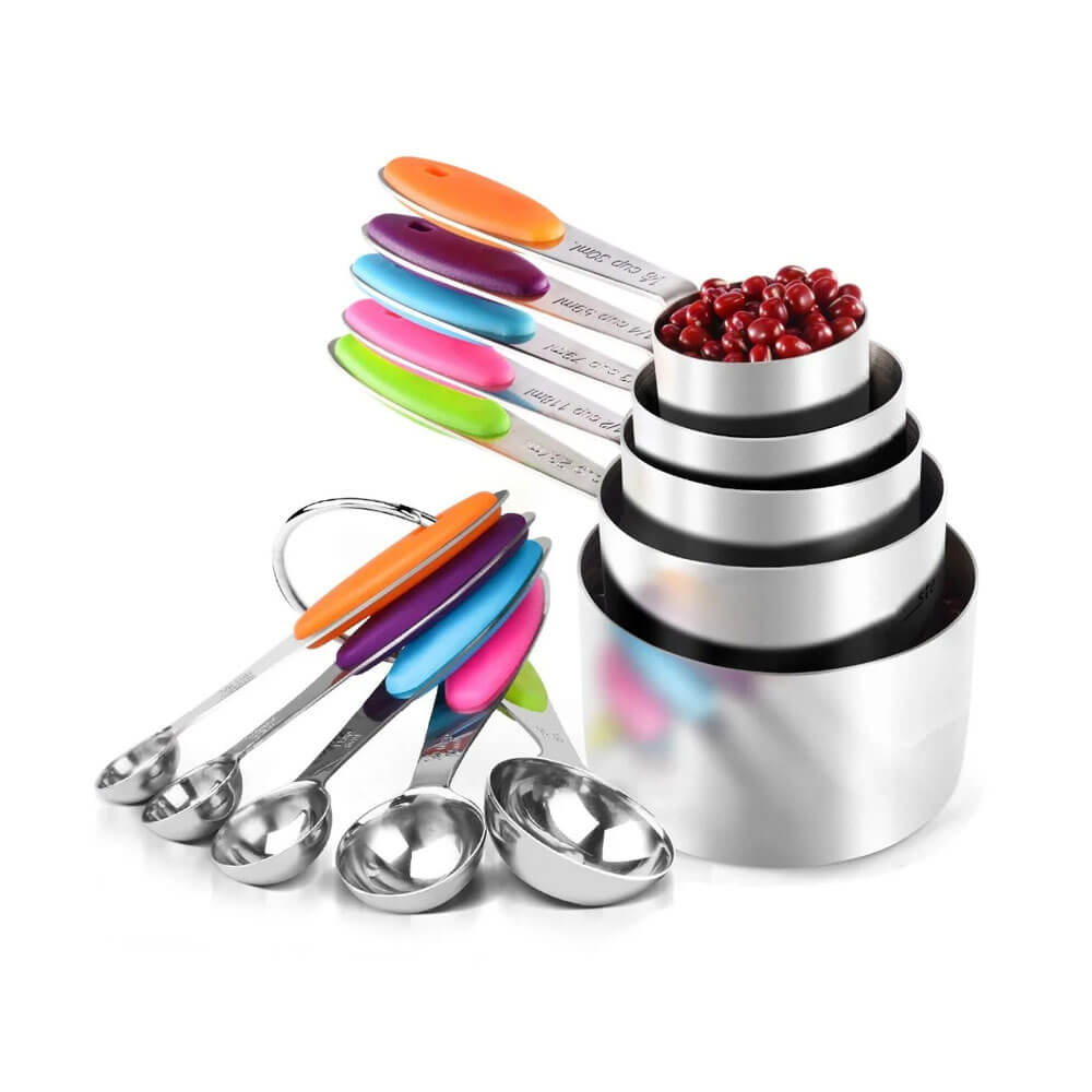 Colorful stainless steel measuring cups and spoons set with engraved measurements, non-slip silicone handles, and a removable metal ring, displayed with stacked cups and arranged spoons.