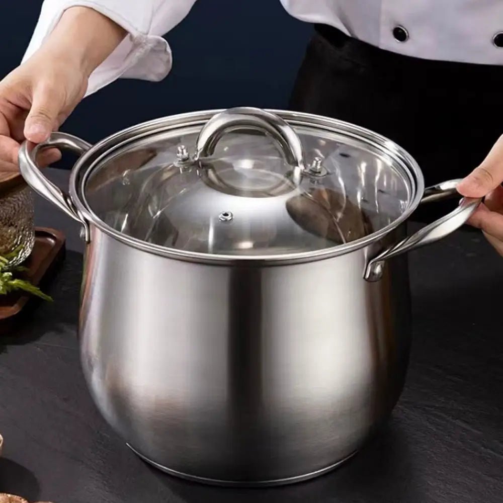 A stainless steel stockpot with a lid held by a person on a dark surface