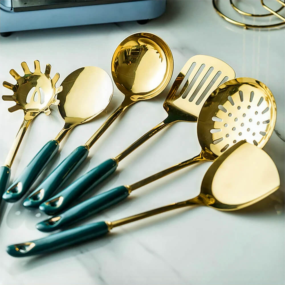 A close-up view of a stylish stainless steel utensils set with a gleaming golden finish and elegant dark teal handles. The set includes six versatile kitchen tools: a spaghetti server, a serving spoon, a ladle, a slotted spatula, a skimmer, and a flat turner. Perfectly designed for modern kitchens, this set combines durability, functionality, and sophistication, making it an essential addition to your cooking essentials.