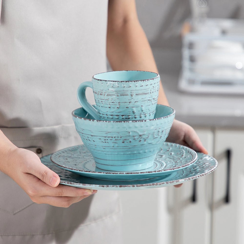 A woman holding a dinner plate, salad plate, mug, and pasta or cereal bowl from a stoneware dinnerware set.