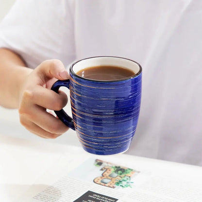 Blue stoneware mug set piece held in hand, filled with coffee, featuring a ribbed textured glaze and white interior.
