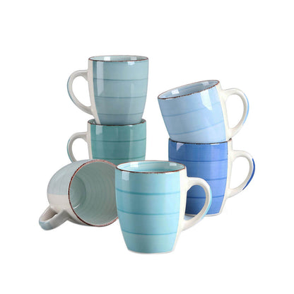 A set of six stoneware mugs in various shades of blue and green is arranged on a plain white background. The mugs feature a smooth striped design with a slightly rustic rim. Some are stacked neatly, while one lies on its side, showcasing the interior.