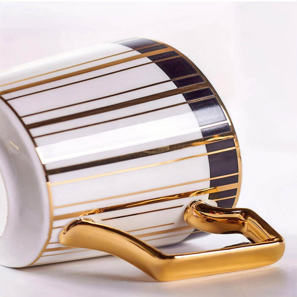 
A close-up view of an elegant tea cup from a tea cups and saucers set, showcasing a luxurious design with vertical black and gold stripes on a white ceramic base.