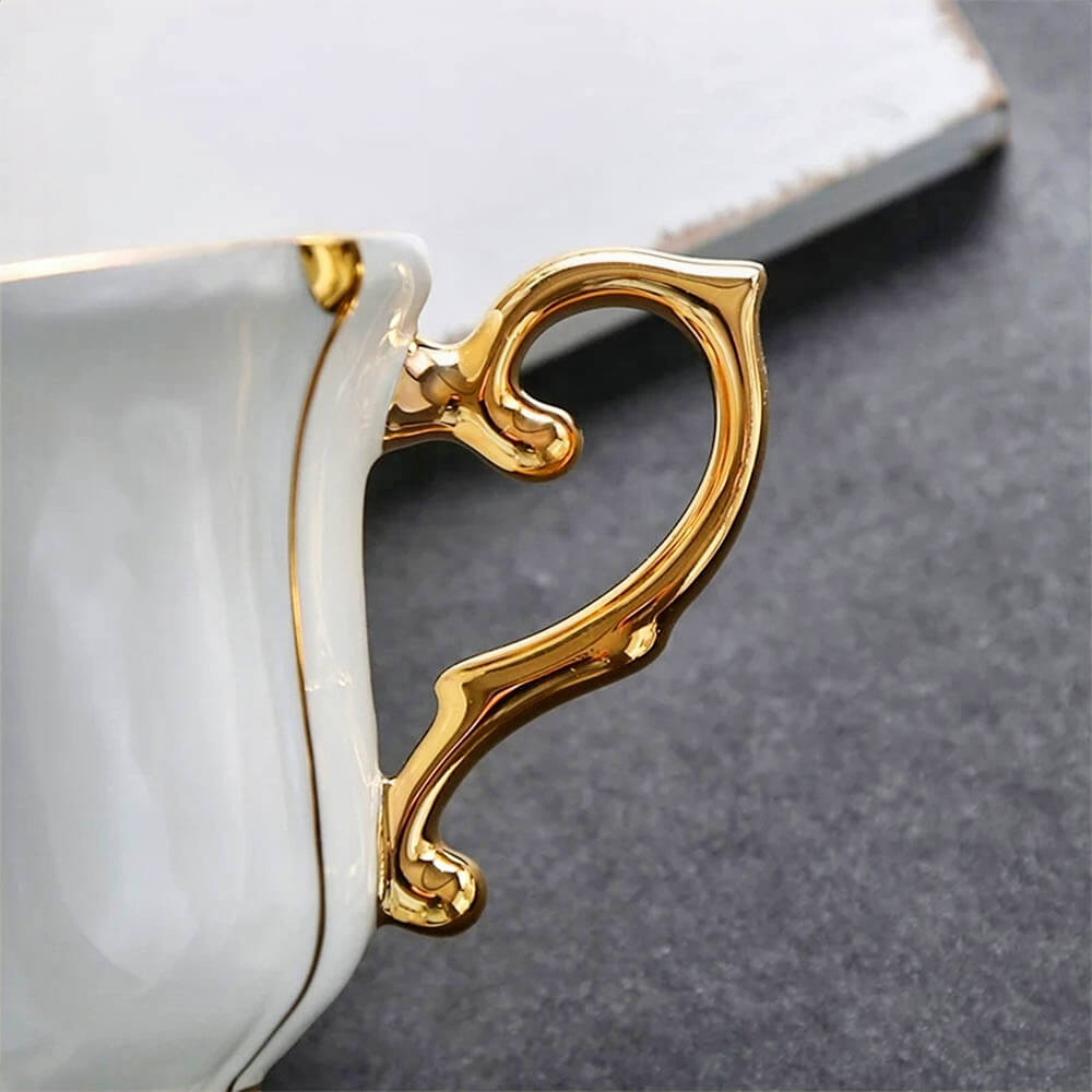 Close-up of an ornate gold handle on a white tea cup, showcasing the luxurious detail of the tea cups saucers set, perfect for elegant tea gatherings.