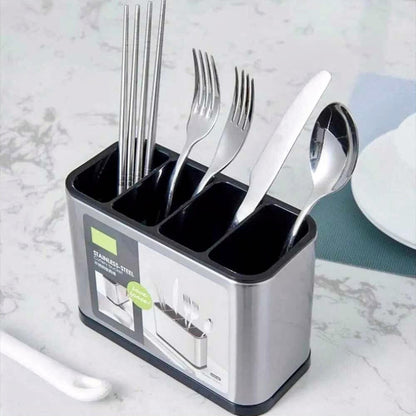 Utensil holder stainless steel with four compartments holding forks, knives, spoons, and chopsticks on a marble kitchen countertop.