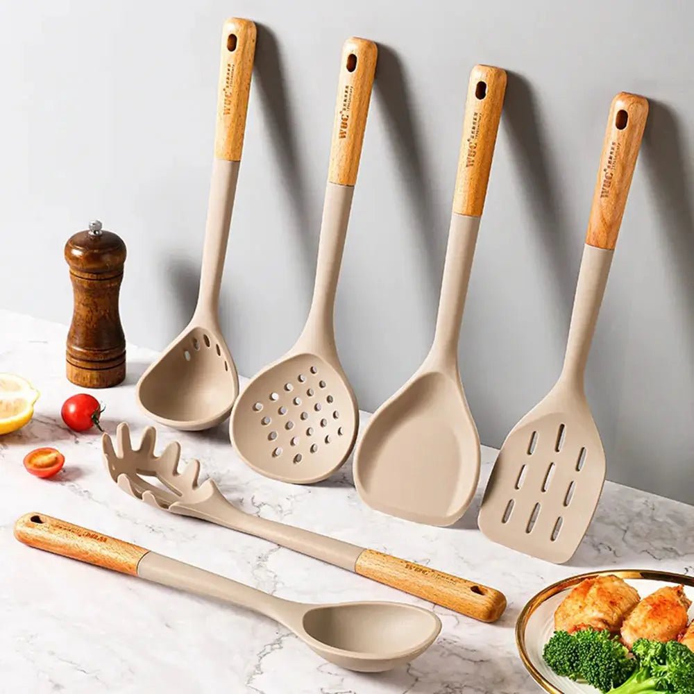Set of beige kitchen utensils with wooden handles on a marble surface.