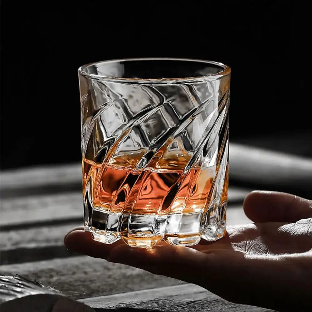 Hand holding a glass of whiskey with a dark background