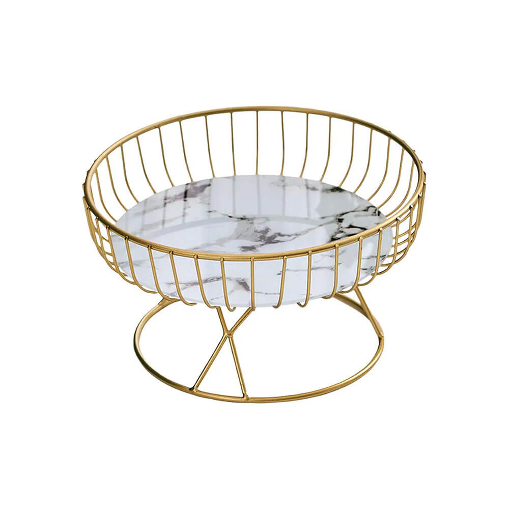 A white pedestal fruit bowl with a round white marble base featuring subtle gray veining. The bowl is surrounded by a sleek gold metal wire frame and supported by a matching gold pedestal stand, offering a modern and elegant design.