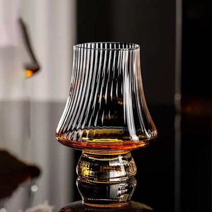 Clear ribbed crystal wine tasting wine glasses with a flared bowl and wide sturdy base, partly filled with amber liquid on a reflective surface.