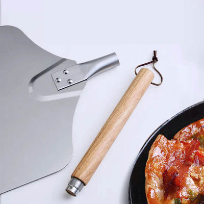 Detachable stainless steel and wooden pizza peel with an oak handle, shown next to a freshly baked pizza on a white surface.