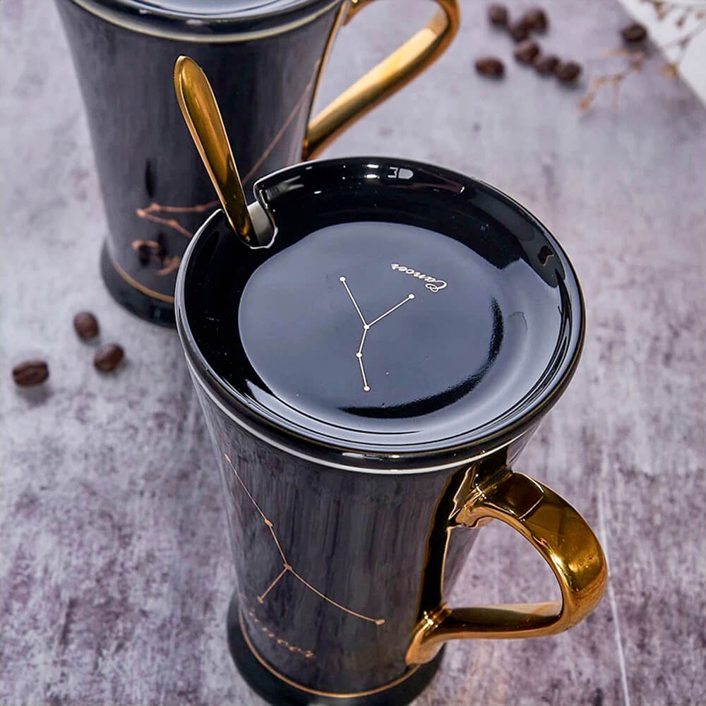 Elegant black zodiac mugs with golden handles and lids, featuring intricate constellation designs, ideal for astrology enthusiasts and coffee lovers.